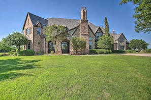 A large, two-story stone house with a prominent chimney, multiple windows, and a well-maintained lawn. - Families Welcome! Lavish Celina Home w/ Game Room (Celina)