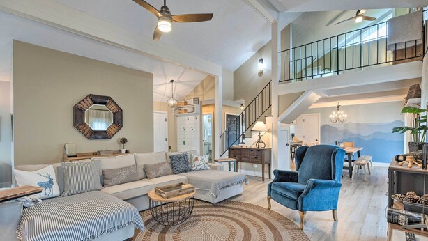 A spacious living room with a sofa, armchair, and a coffee table. There is a staircase leading to an upper level. - Pet-friendly Massanutten Resort Home w/ Yard! (McGaheysville)