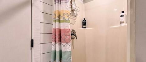 Zona de ducha con cortina, secamanos y dos botellas de champú.