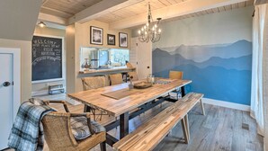 A cozy dining area with a wooden table, benches, wicker chairs, and a mural of mountains on the wall. - Pet-friendly Massanutten Resort Home w/ Yard! (McGaheysville)