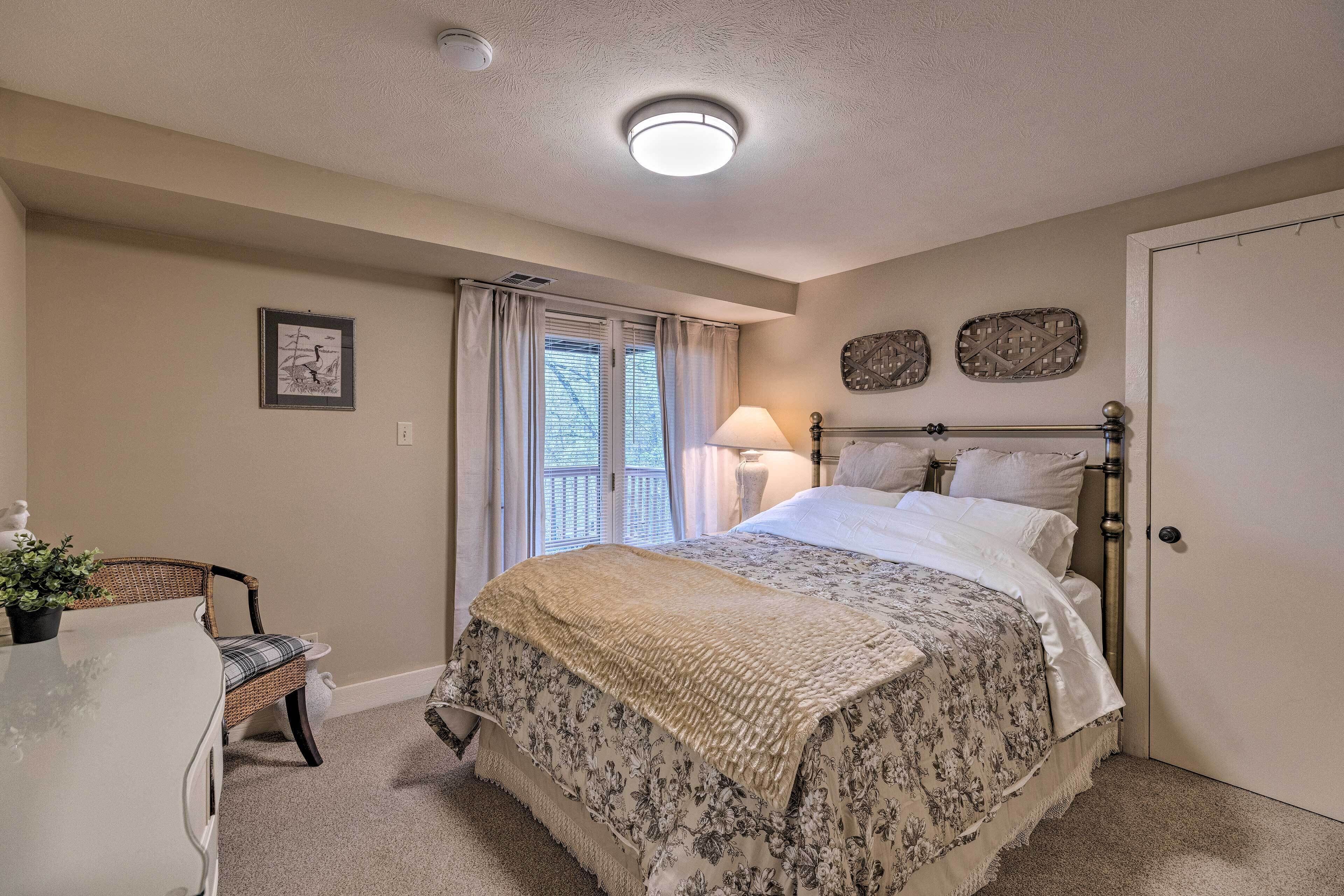 A bedroom with a bed, a chair, a bedside table, a lamp, and a door.