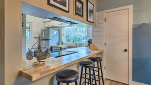 A kitchen with a wooden countertop, bar stools, a hanging light fixture, and framed pictures on the wall. - Pet-friendly Massanutten Resort Home w/ Yard! (McGaheysville)