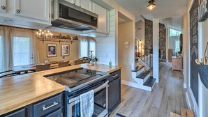 A modern kitchen with a central island, stainless steel appliances, and a stone accent wall. - Pet-friendly Massanutten Resort Home w/ Yard! (McGaheysville)