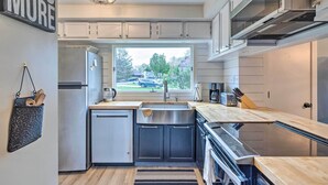 A modern kitchen with white cabinets, a stainless steel refrigerator, a built-in oven, and a window with a view of the outside. - Pet-friendly Massanutten Resort Home w/ Yard! (McGaheysville)