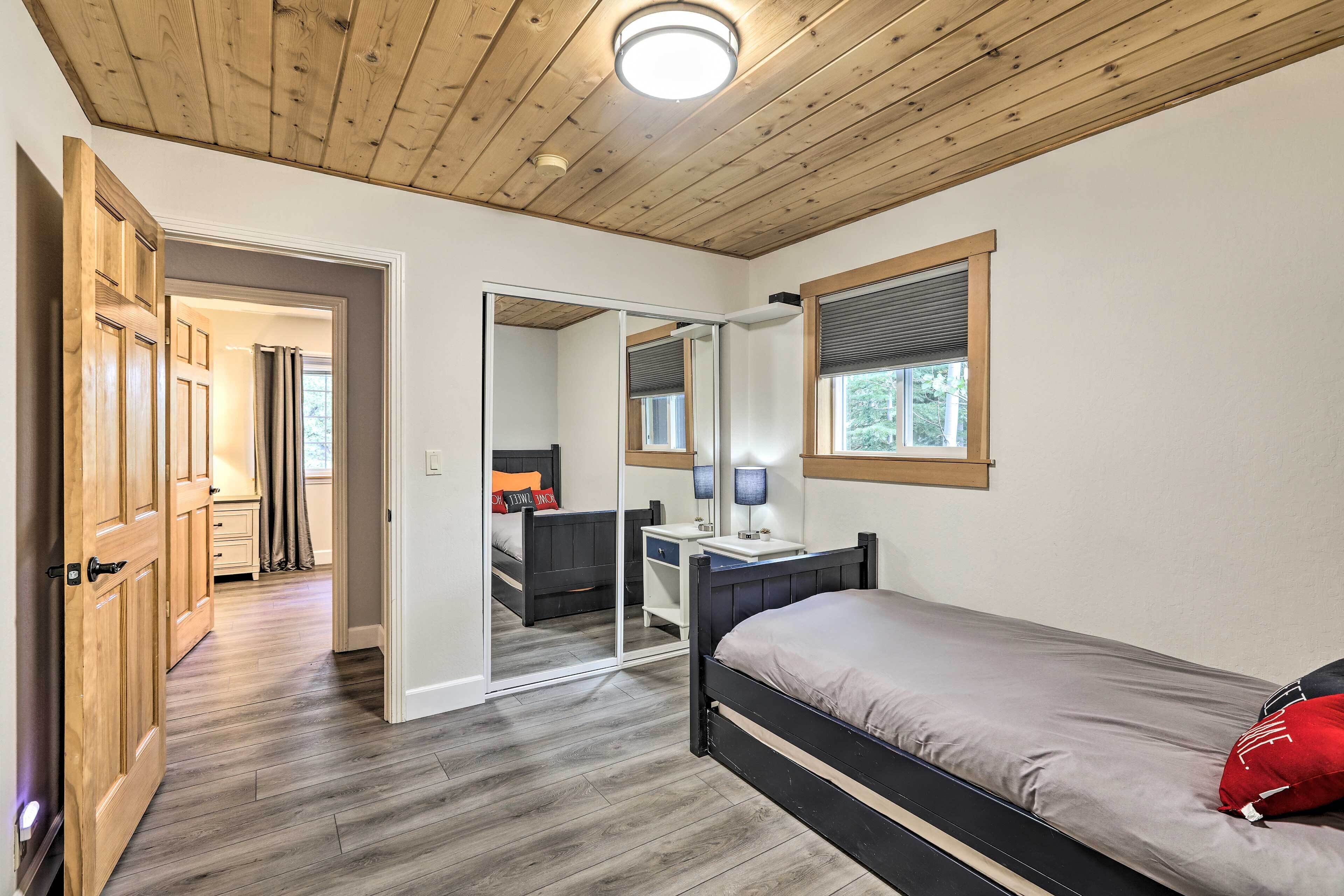 Un dormitorio con techo de madera, una cama, un escritorio, un espejo y una ventana.