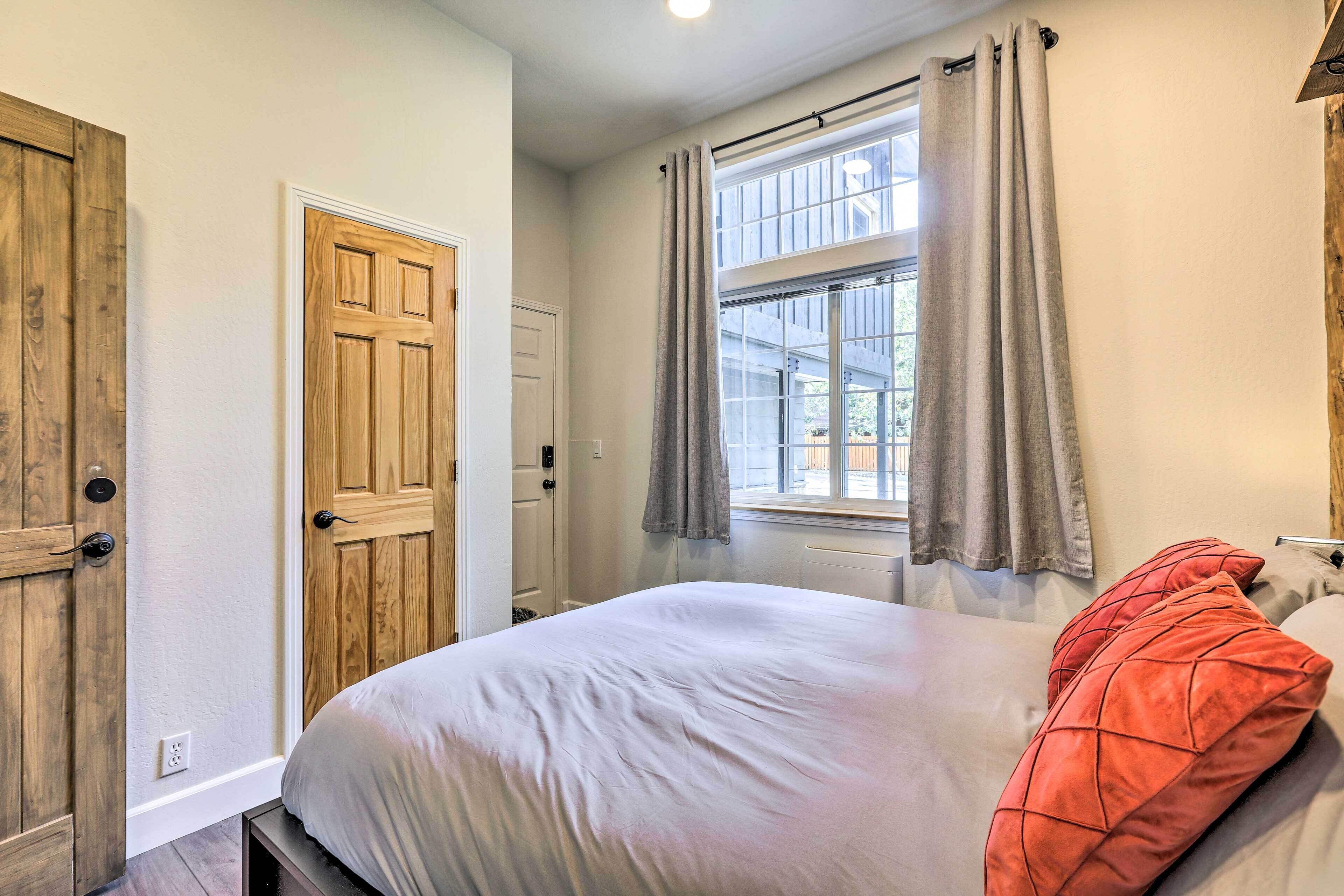 Une chambre à coucher avec un lit, des portes en bois, une fenêtre avec des rideaux et un radiateur.