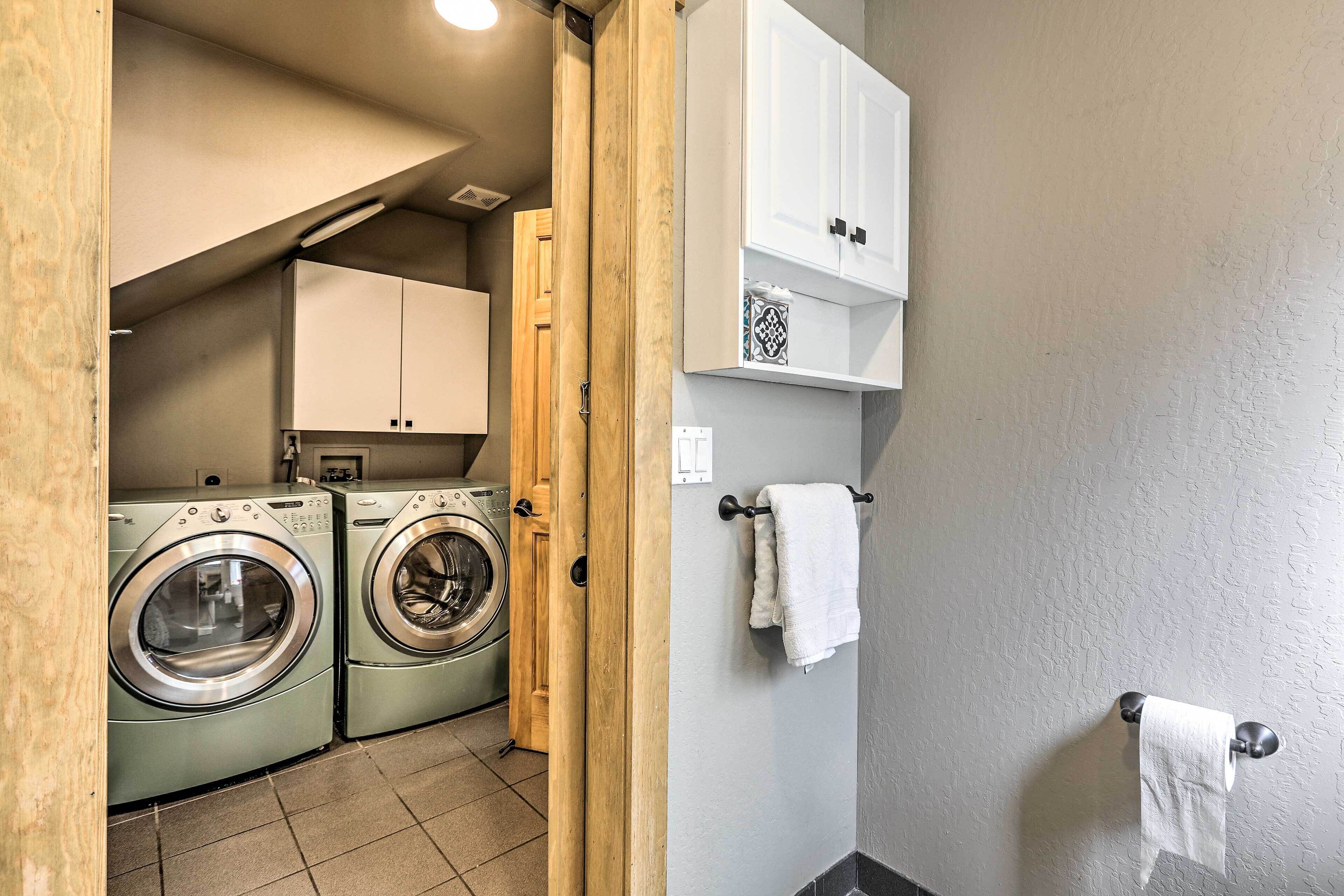 A laundry room with two front-loading washing machines, wooden cabinets, and a towel rack.