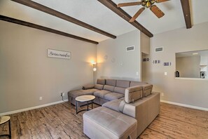 A modern living room with a sectional sofa, a small round table, and a ceiling fan. - 1/2 Mi to Spring Training! Condo w/ Patio in Tempe (Tempe)