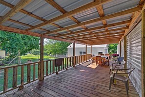 A covered porch with wooden beams and a metal roof, featuring a dining table and chairs, a grill, and a view of a yard and house in the background. - Waterloo Home With Fire Pit - 1/2 Mi to Boat Ramp! (Waterloo)