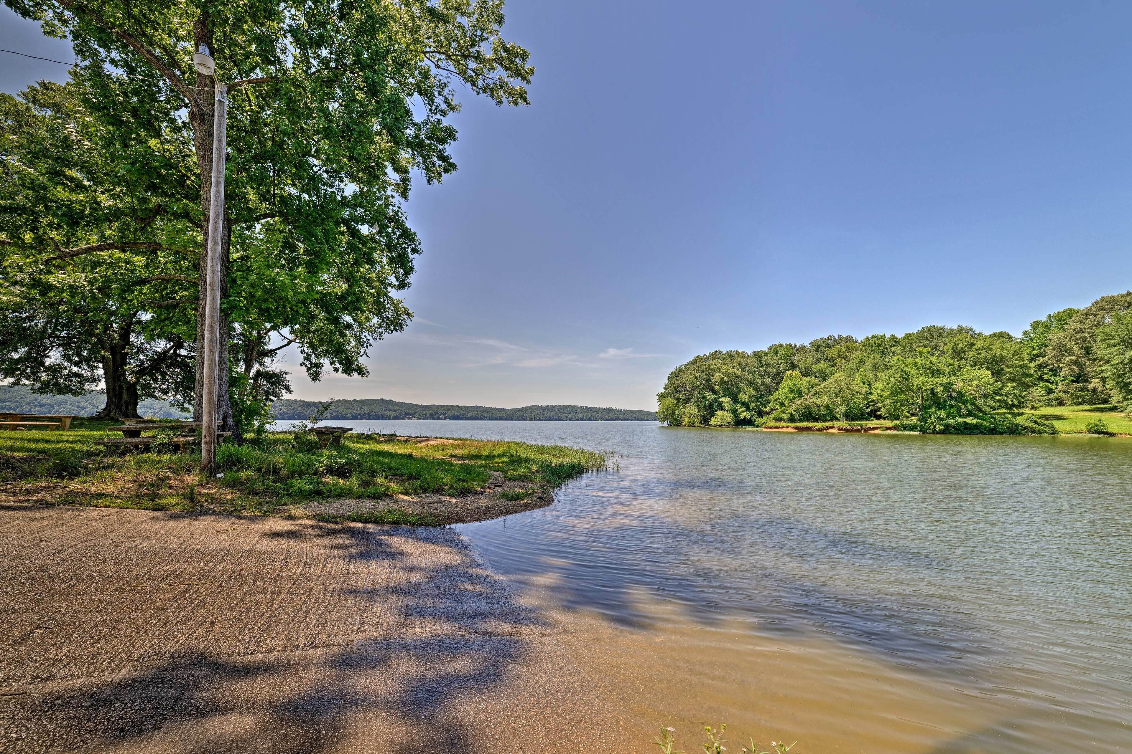Une vue sur le lac, avec un espace pique-nique, un banc en bois et un ciel dégagé.