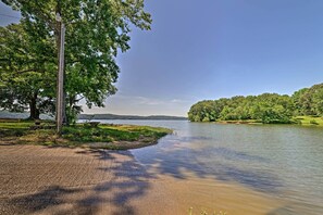 A lakeside view with a picnic area, a wooden bench, and a clear sky.