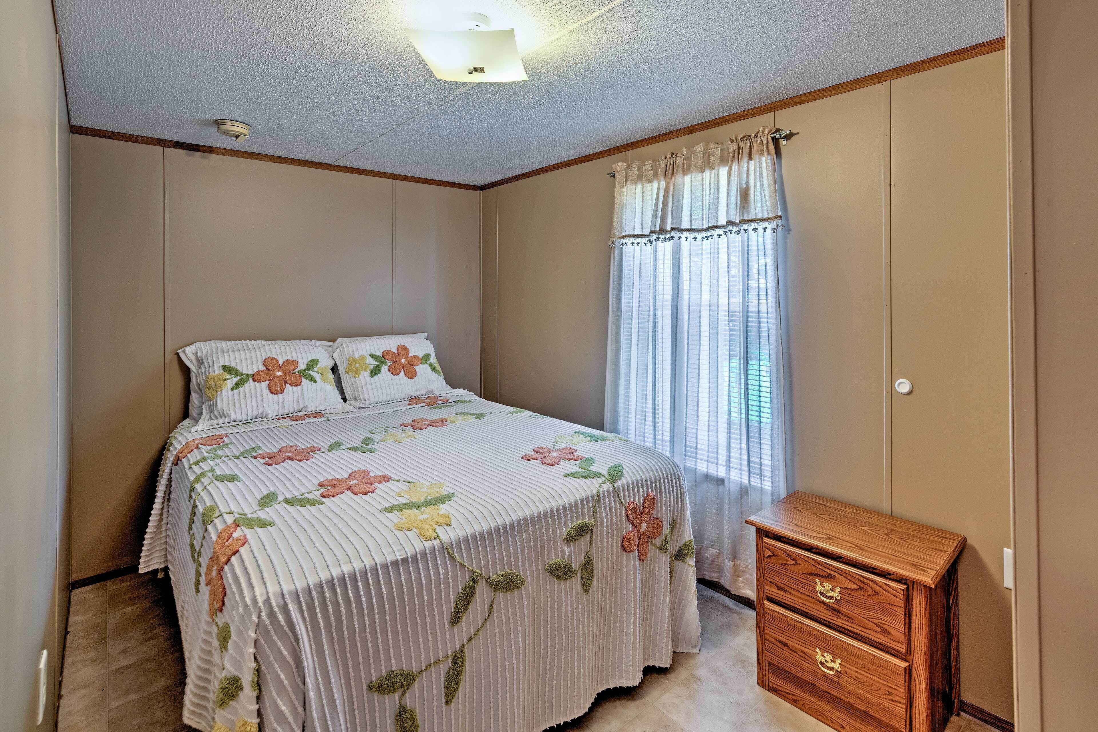 Une chambre à coucher avec un lit, une commode en bois et une fenêtre avec des rideaux.