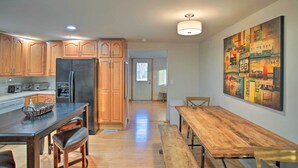 A modern kitchen with wooden cabinets, a black refrigerator, and a dining area with a wooden table and chairs.