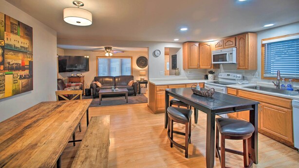 A modern kitchen with wooden cabinets, a central island, and a dining area with a wooden table and bar stools.