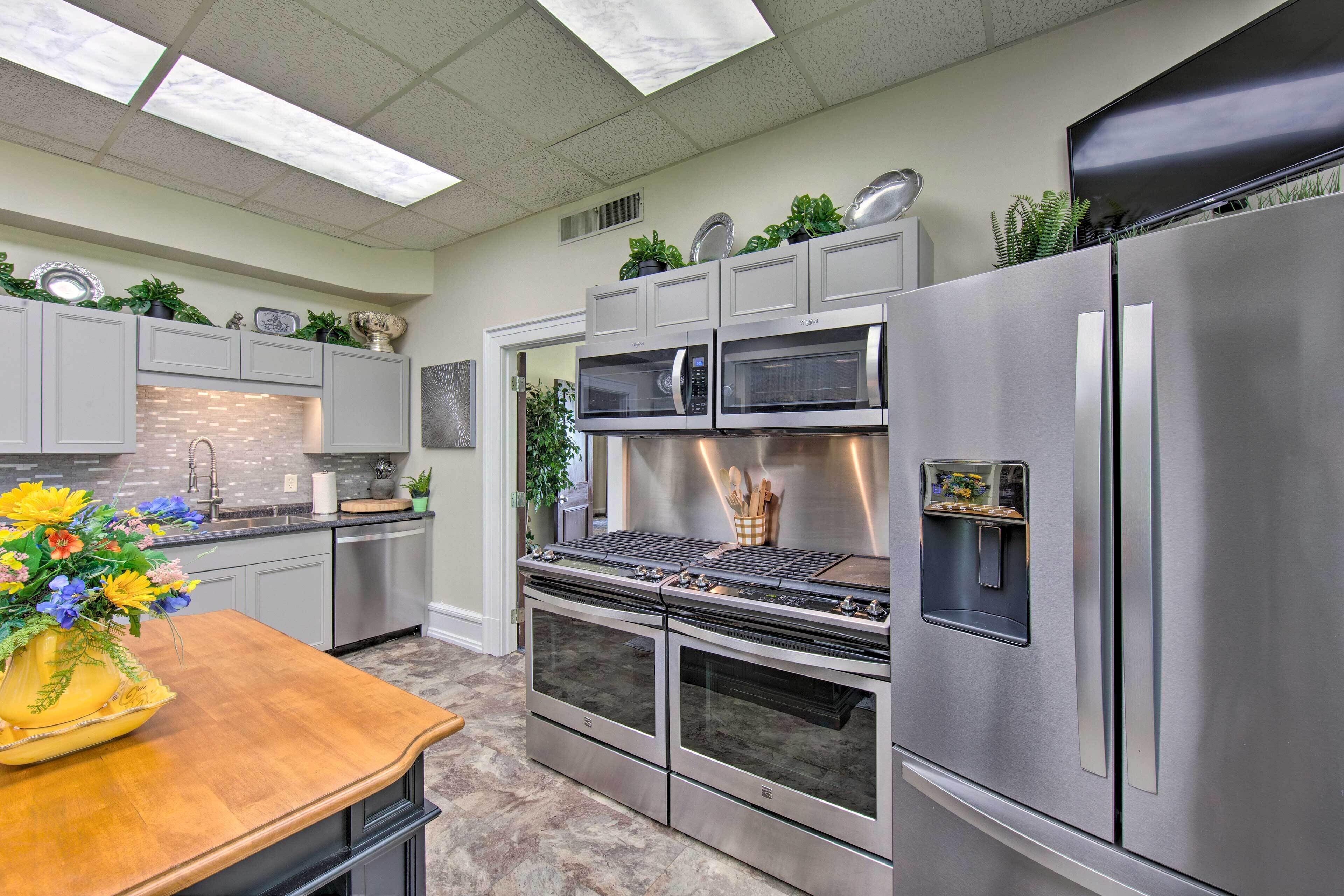 A modern kitchen with stainless steel appliances, a wooden countertop, and decorative plants.