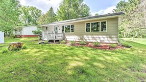 A single-story house with a front porch, a small deck, and a well-maintained lawn. - Fishermen's Paradise w/ Fire Pit on Rice Lake! (Rice Lake)