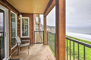 Un balc ón con vista al océano, una silla y una escalera que lleva a un nivel superior.