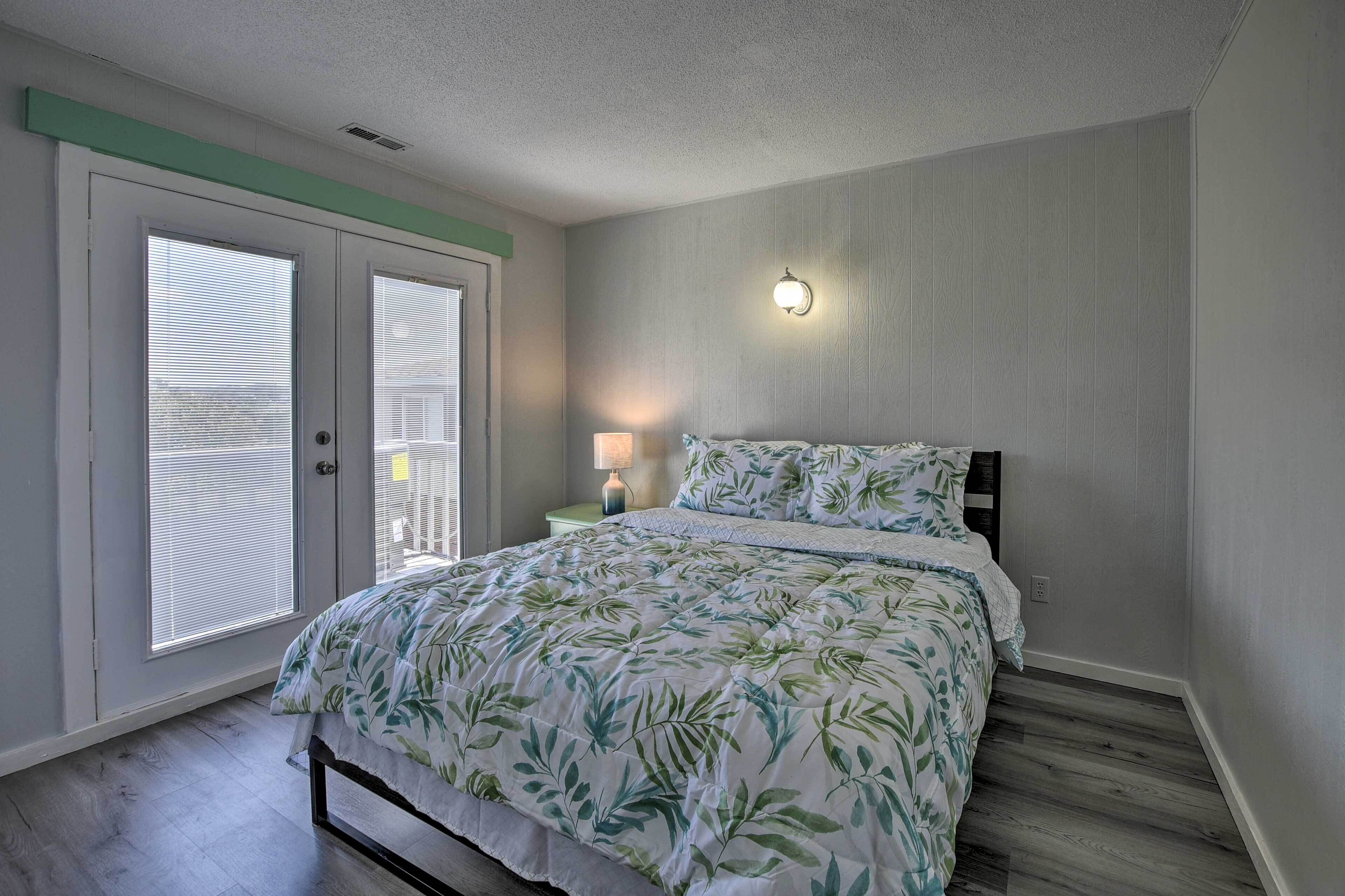 A bedroom with a bed, a nightstand, a lamp, and a wall-mounted light fixture.