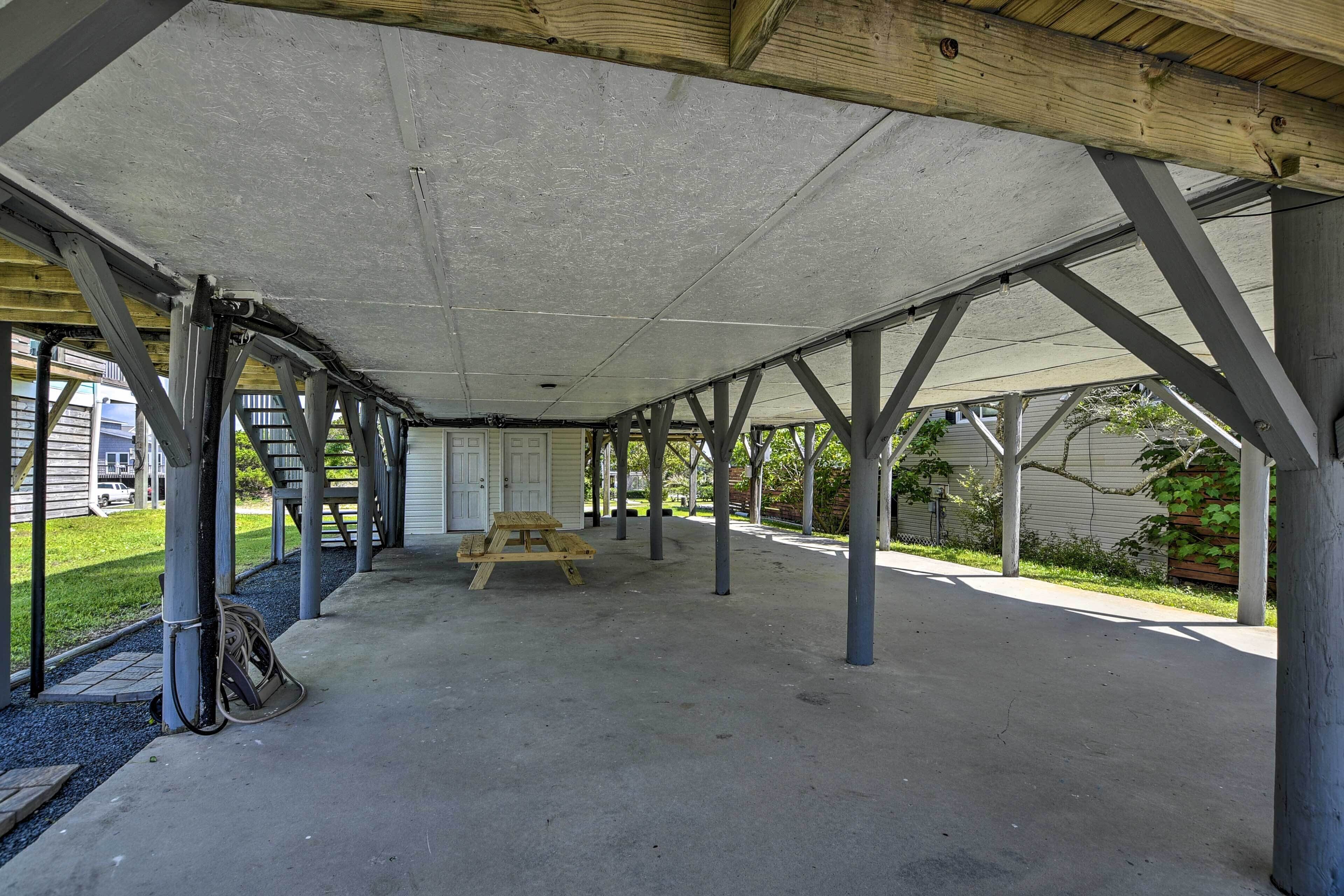 Un patio couvert comprenant une table de pique-nique, un sol en béton et des poutres métalliques soutenant la structure.