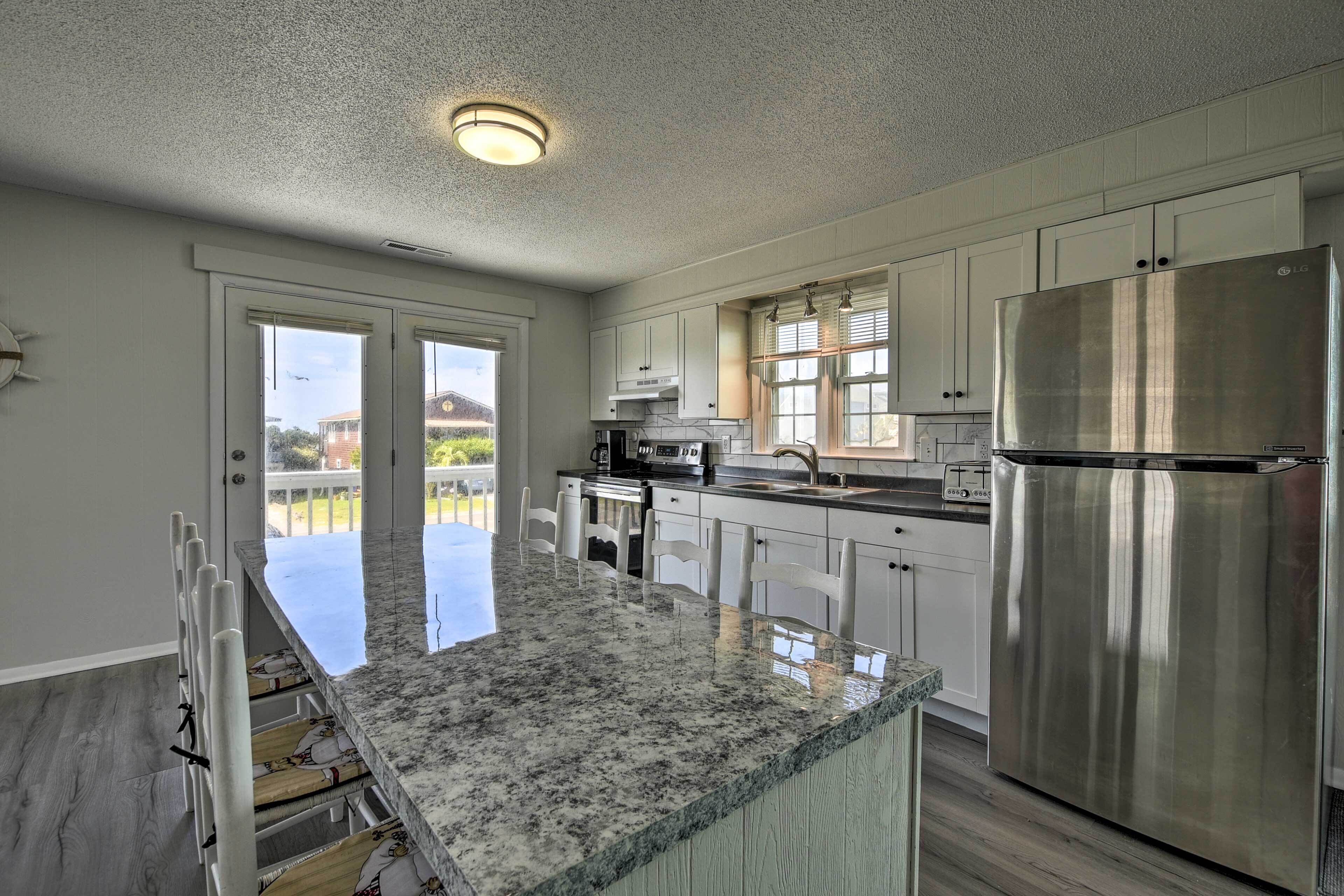 A modern kitchen with white cabinets, a stainless steel refrigerator, and a granite countertop.