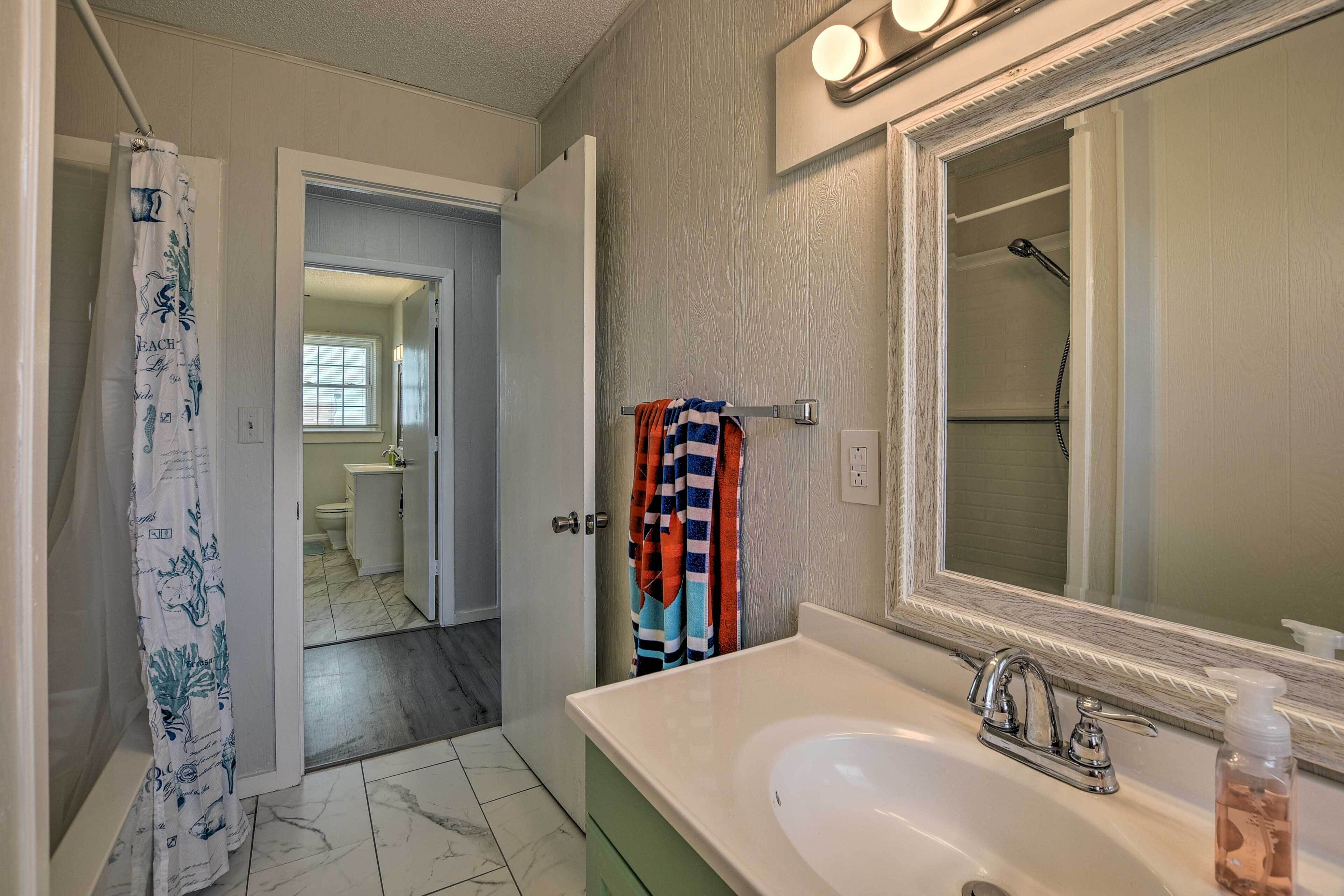 Une salle de bain avec un lavabo blanc, un miroir et un rideau de douche.