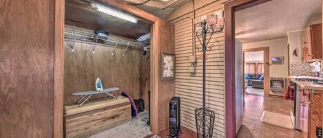 A room with a wooden floor, a patterned rug, a ceiling fan, and a wall-mounted ironing board.