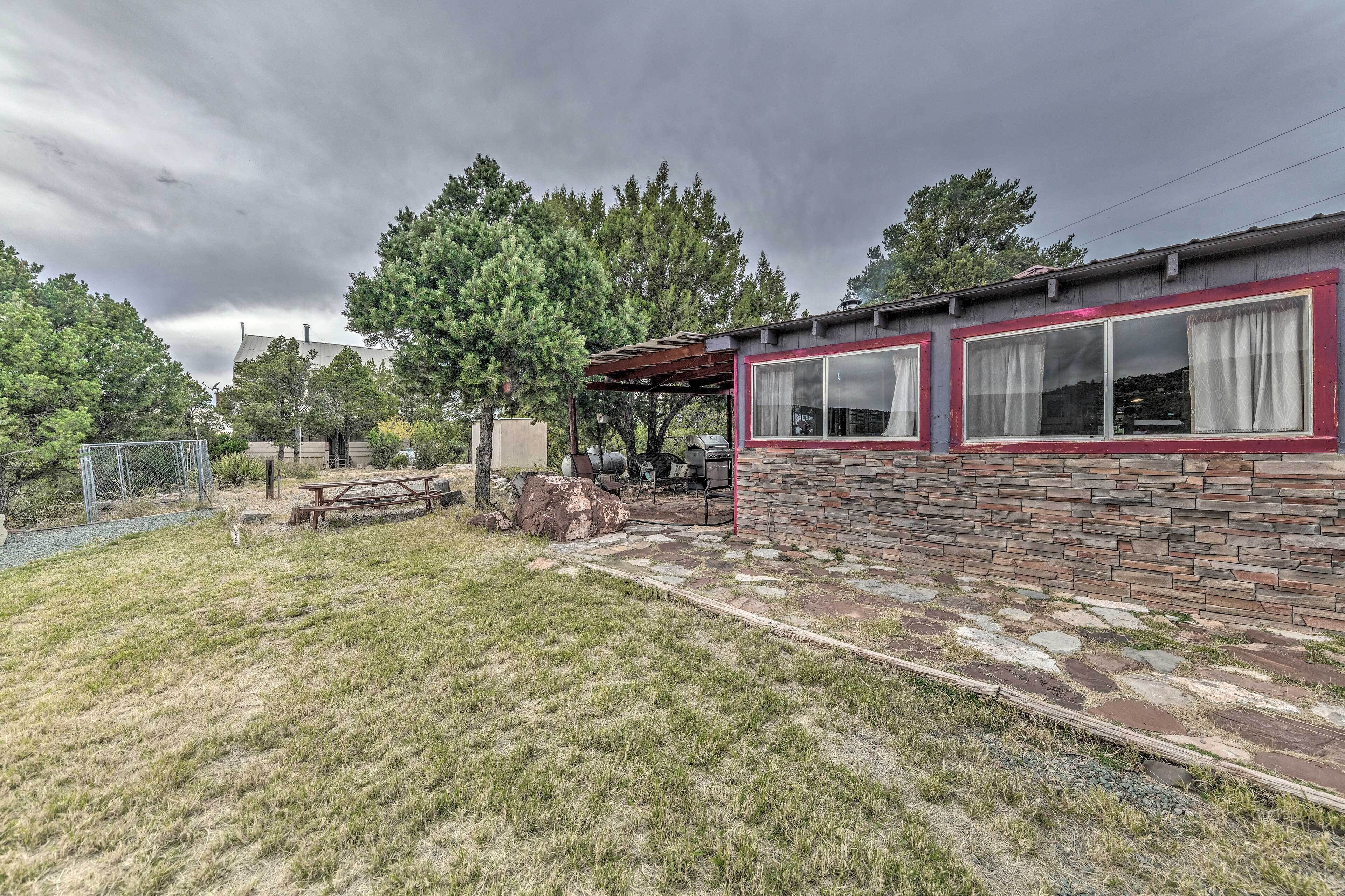 A rustic cabin with a stone exterior and a red trim, a picnic table, and a covered outdoor seating area.