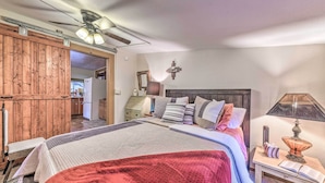 A bedroom with a bed, bedside table, lamp, and a wooden wardrobe. - Cozy High Rolls Cottage Near Hiking Trails! (High Rolls Mountain Park)