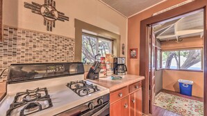 A compact kitchen with a gas stove, a microwave, and a window. - Cozy High Rolls Cottage Near Hiking Trails! (High Rolls Mountain Park)