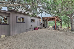 A house with a gravel driveway, a covered patio, and a large tree providing shade. - Cozy High Rolls Cottage Near Hiking Trails! (High Rolls Mountain Park)