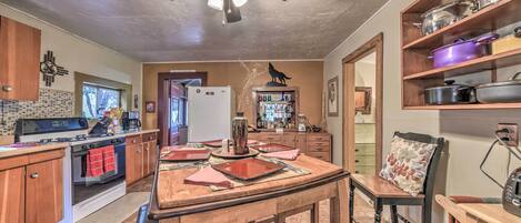 A kitchen with wooden cabinets, a stove, a ceiling fan, and a dining area with a table and chairs.