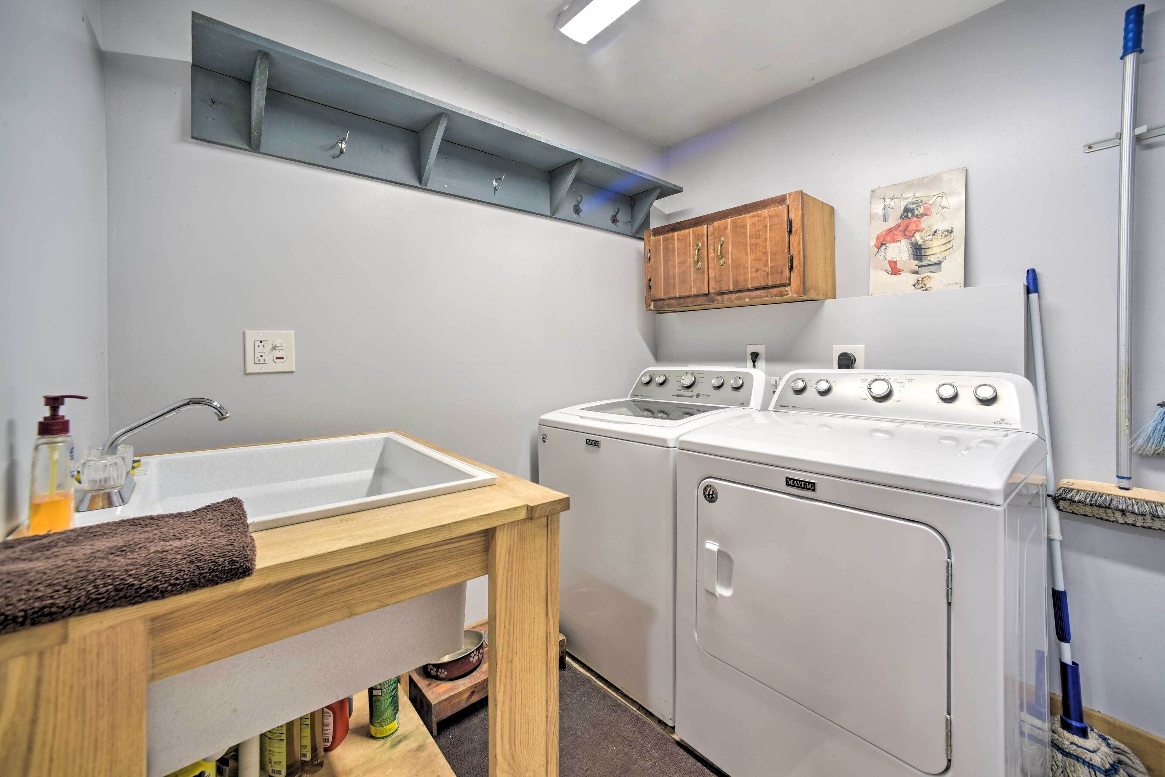 A compact laundry room with a sink, two dryers, and a wooden table.