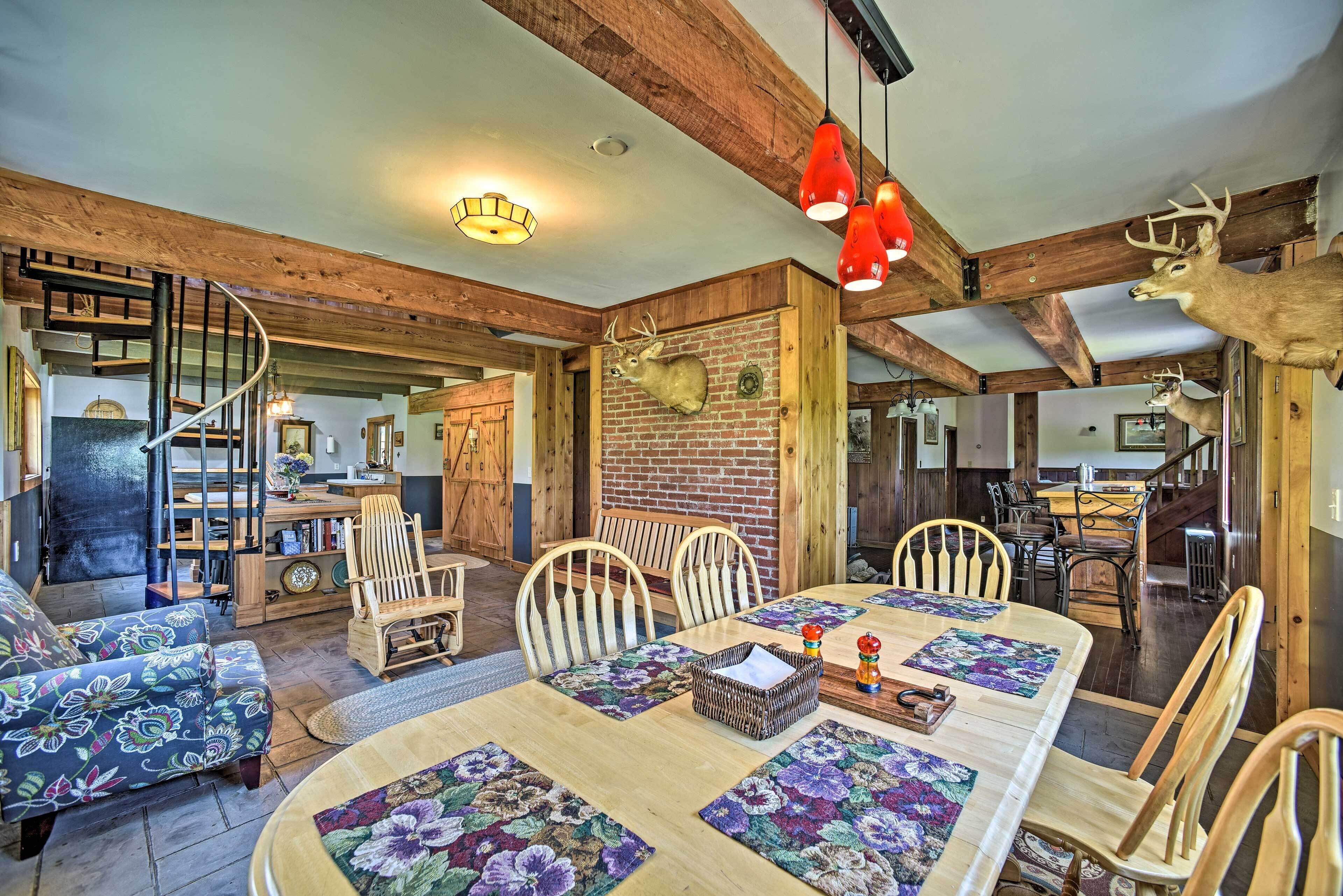 A rustic dining area with a wooden table, chairs, and a chandelier.
