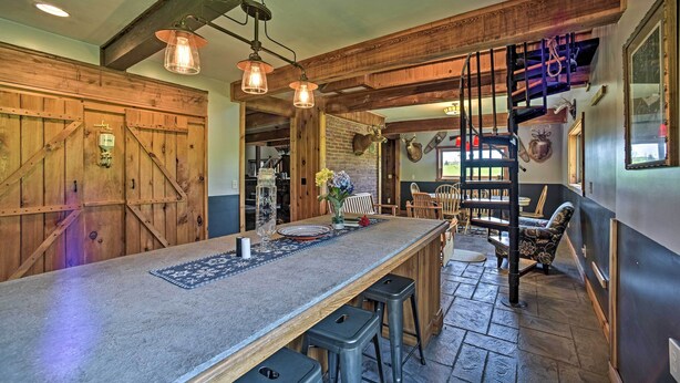 A rustic interior with a long wooden bar, stone flooring, and wooden beams.