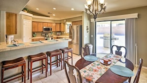A kitchen with wooden cabinets, a central island, stainless steel appliances, and a dining area with a table and chairs. - Fort Mohave Home < 8 Mi to Colorado River! (Fort Mohave)