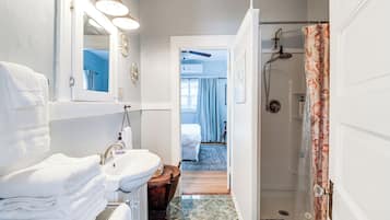 A bathroom with a sink, mirror, and shower.