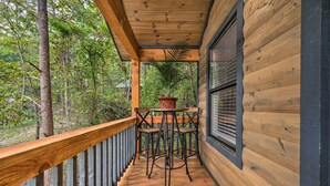 Une terrasse en bois avec une rambarde, une table avec des chaises et une plante en pot.
