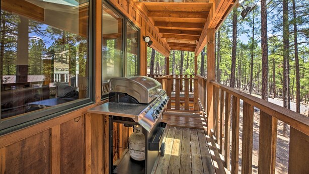 Eine Holzterrasse mit Grill und Glastür, die zu einem Raum führt.