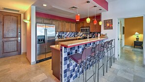 A modern kitchen with a central island, stainless steel appliances, and a bar area with stools. - Paraiso del Mar Resort Condo: Water Taxi to La Paz (La Paz)