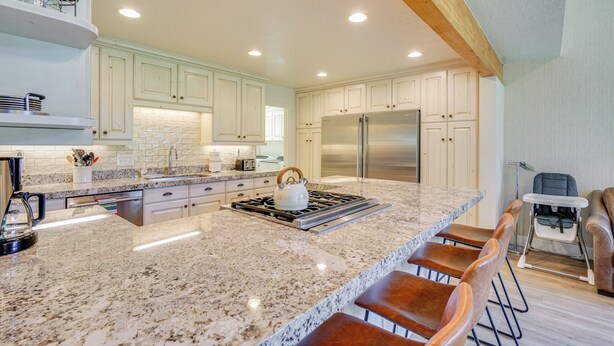 A modern kitchen with granite countertops, stainless steel appliances, and a bar area with stools. - Superb Park City Escape w/ Deck, Walk to Ski Lift! (Park City)