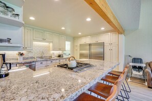 A modern kitchen with granite countertops, stainless steel appliances, and a bar area with stools. - Superb Park City Escape w/ Deck, Walk to Ski Lift! (Park City)