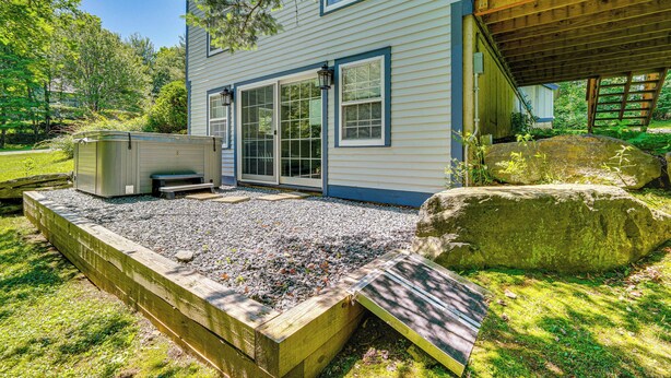Ein Haus mit überdachter Terrasse, Whirlpool und Steinelement.