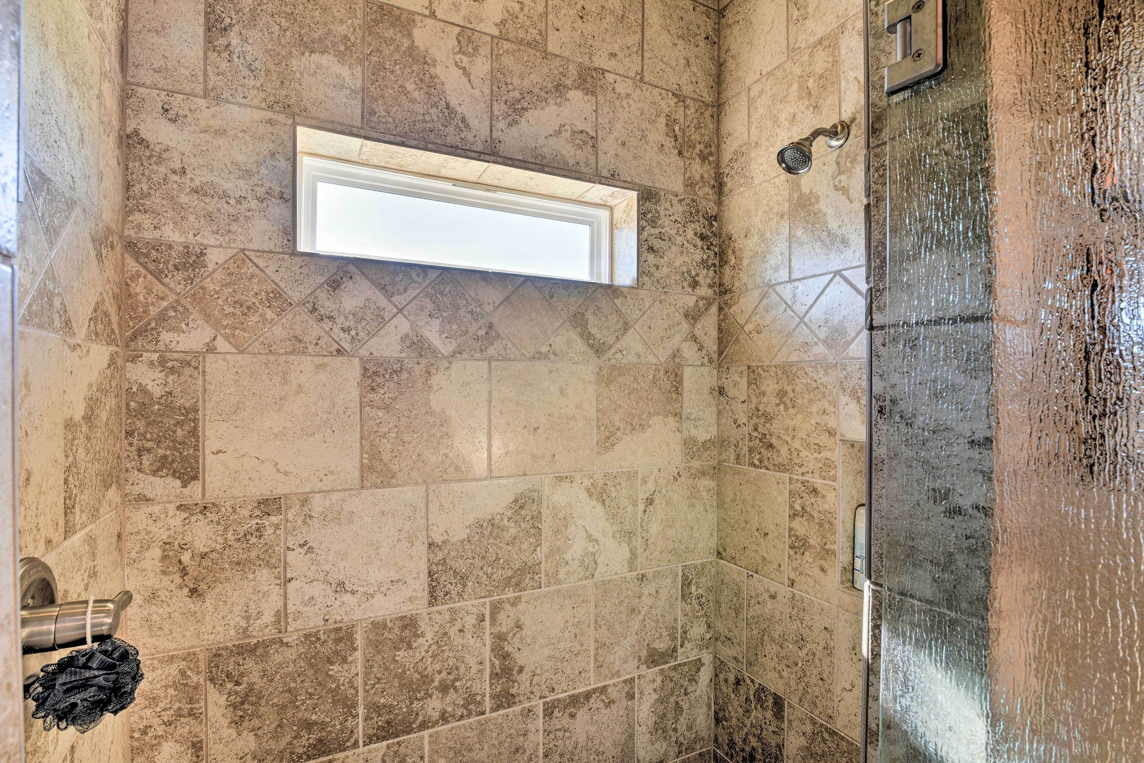 A bathroom with a shower, tiled walls, and a visible towel rack.