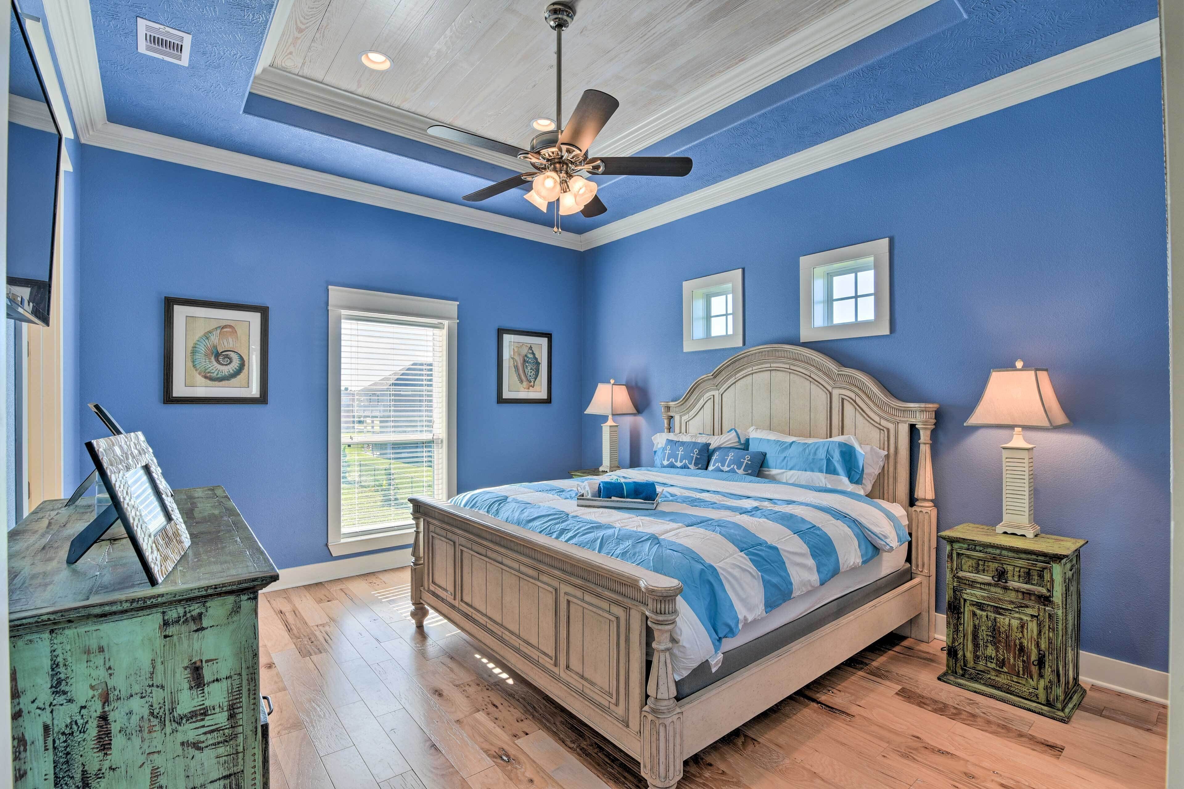 A bedroom with a bed, a ceiling fan, a nightstand, and a dresser.