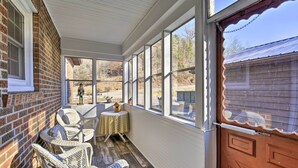 Une véranda aménagée avec des meubles en osier, une petite table et une vue sur le jardin arrière.