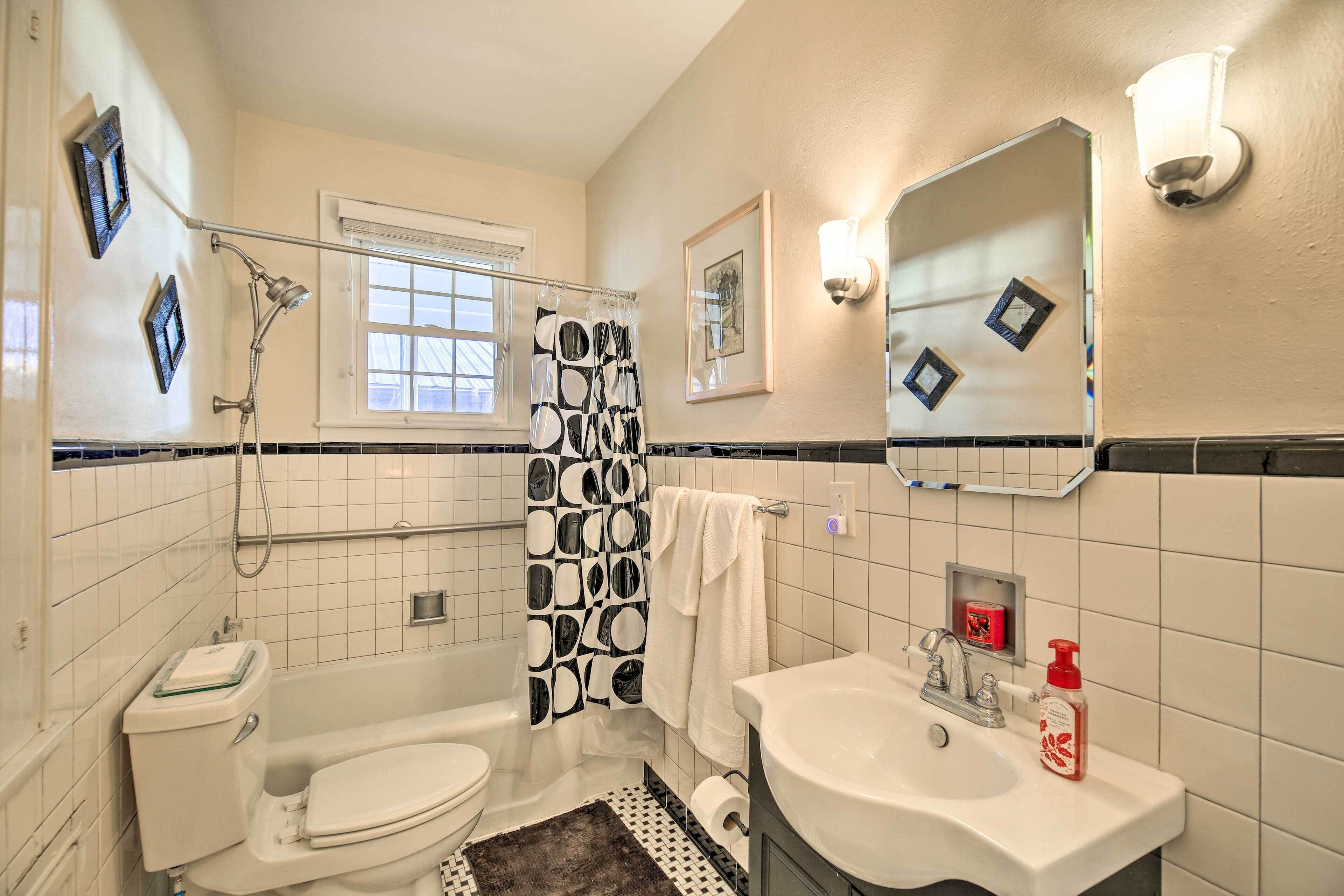 A bathroom with a toilet, sink, shower, and a mirror.