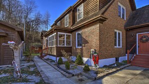 Une maison à deux étages, construite en briques, avec un porche à l’avant, un petit jardin aux arbustes taillés et une guirlande décorative accrochée à la porte.