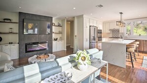 A modern kitchen with white cabinets, a central island with bar stools, a built-in oven, and a large window providing a view of the outdoors. - Updated Getaway w/ Pool & Hot Tub on < 3 Acres! (Stony Point)