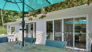 An outdoor patio with a wooden table, blue cushioned chairs, and a teal umbrella. - Updated Getaway w/ Pool & Hot Tub on < 3 Acres! (Stony Point)