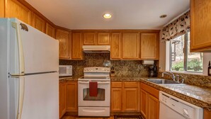 Una cocina compacta con armarios de madera, un refrigerador blanco, una estufa, un microondas y un lavavajillas.